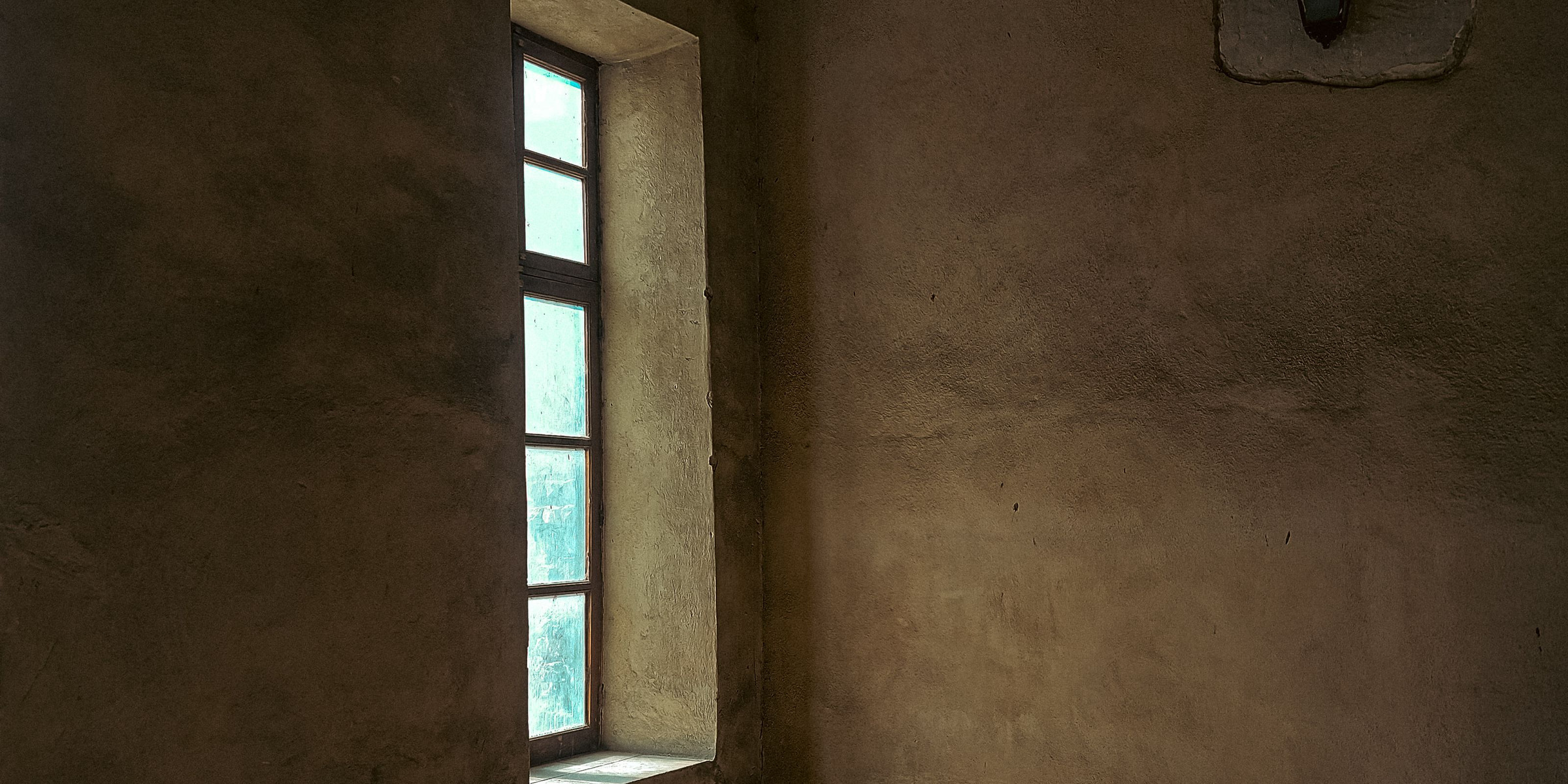 Kleines Fenster in einem leeren Raum mit Lehmwand