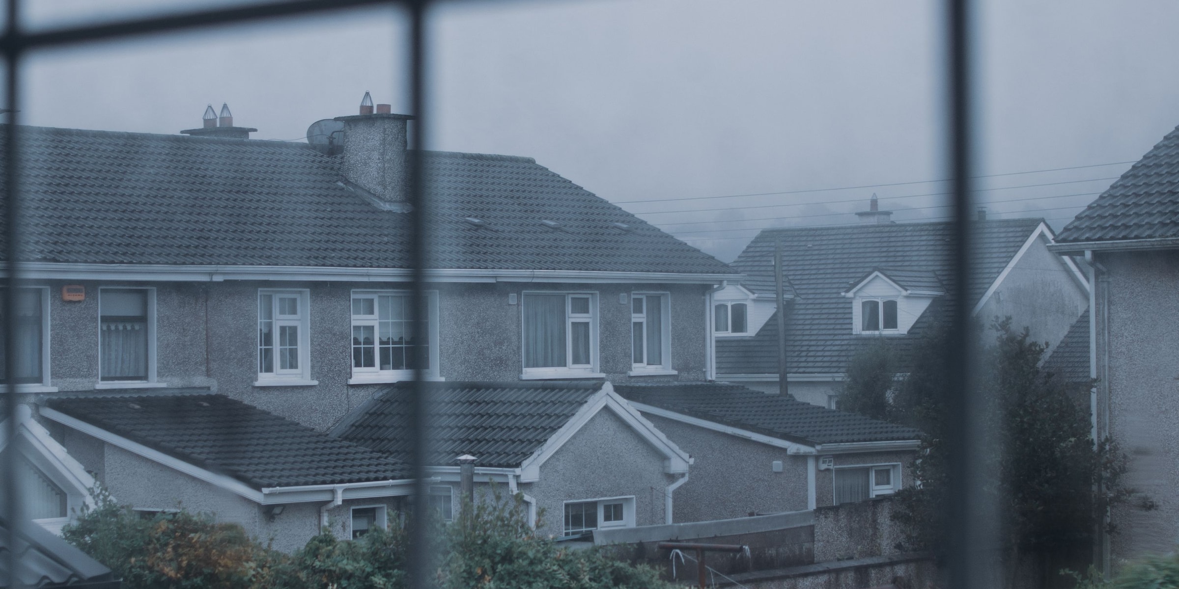 Wohnstraße mit mehreren Hausdächern, durch eine Fensterscheibe fotografiert