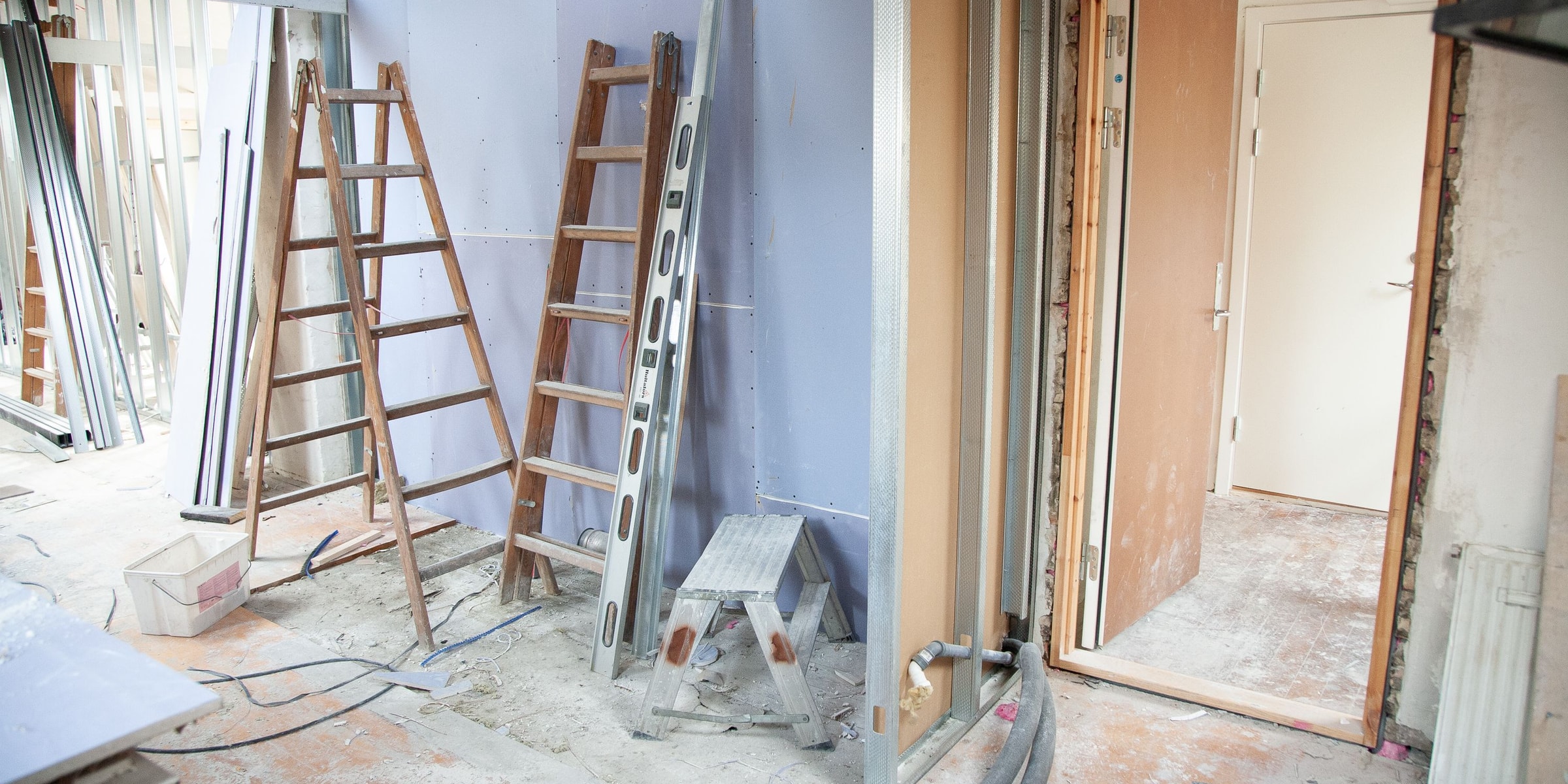 Holzleitern, Werkzeug und eine offene Tür in einer im Umbau befindlichen Wohnung