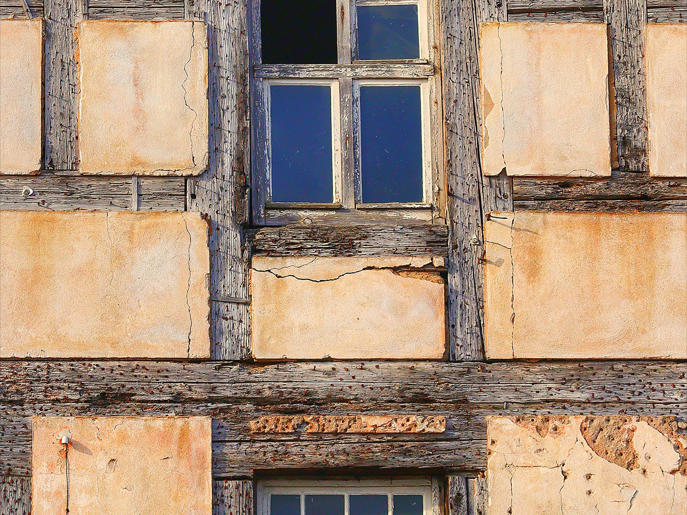 Verwitterte Fachwerkfassade mit alten Holzbalken und einem Fenster