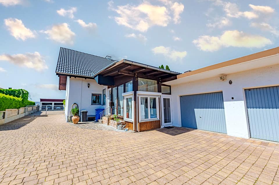 Hofseite des Hauses mit überdachter Terrasse, Anbau und zwei Garagentoren