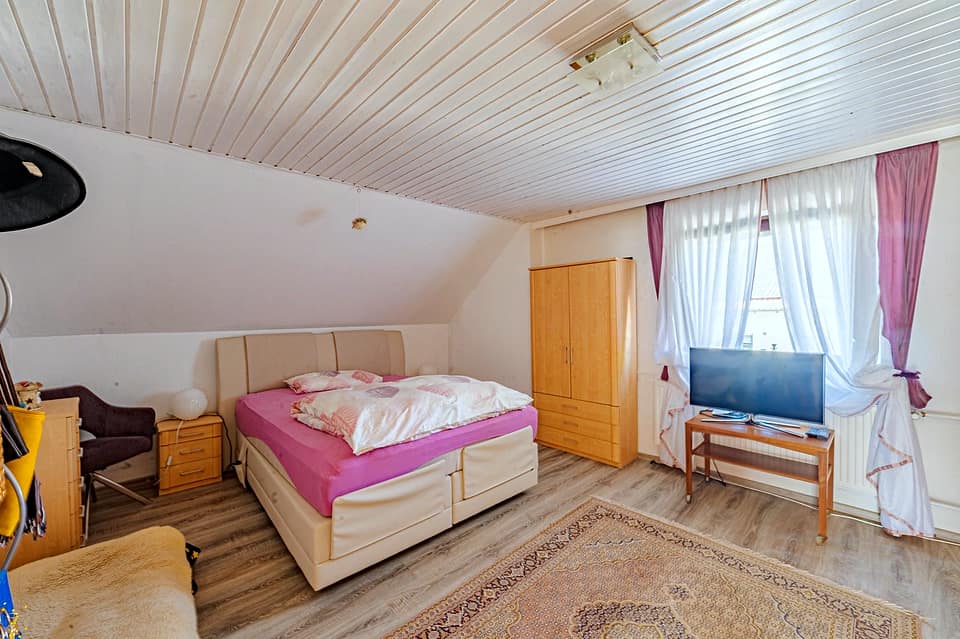 Zweites Schlafzimmer mit Doppelbett, Kleiderschrank und Teppich auf Dielenboden