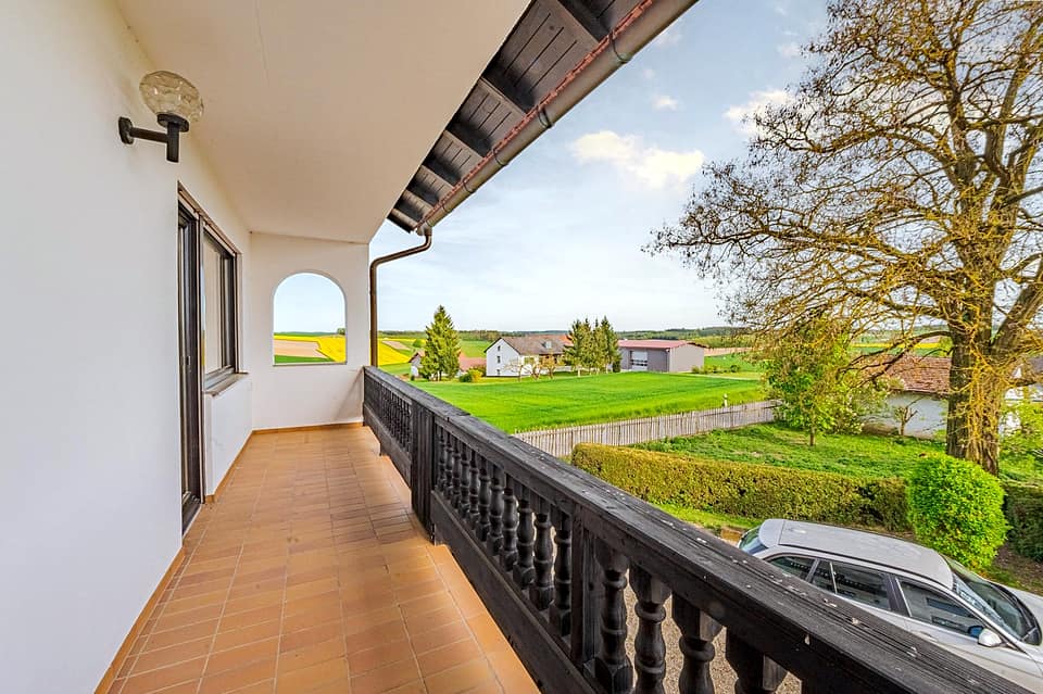 Überdachter Balkon mit Betongeländer und Blick über die Felder