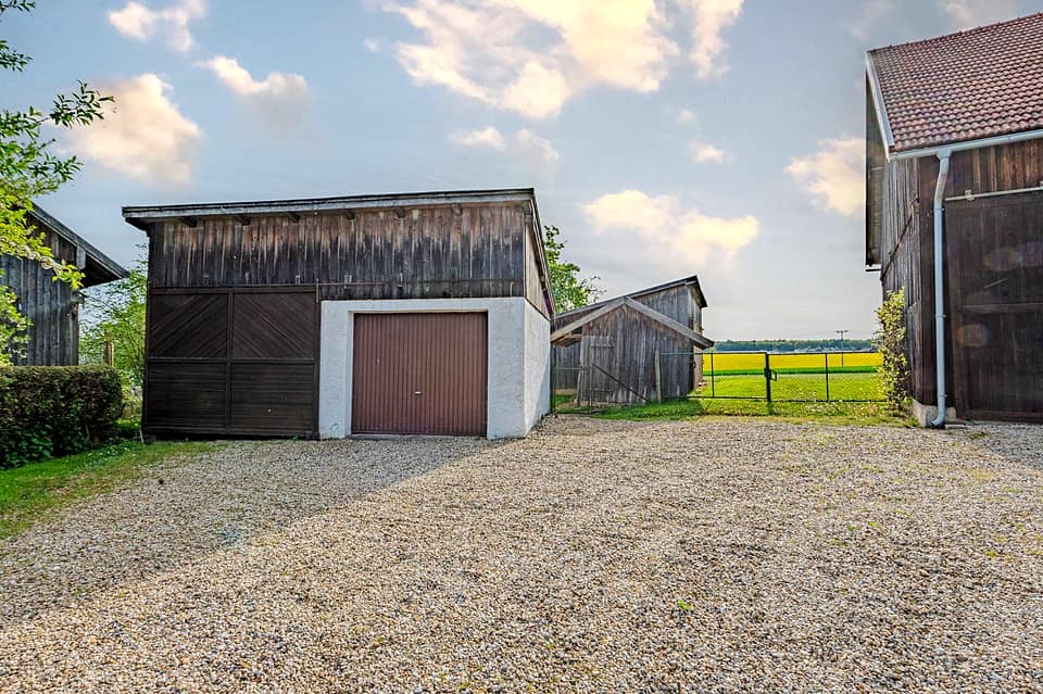 Garage mit Rolltor neben der Scheune, davor eine Kiesfläche