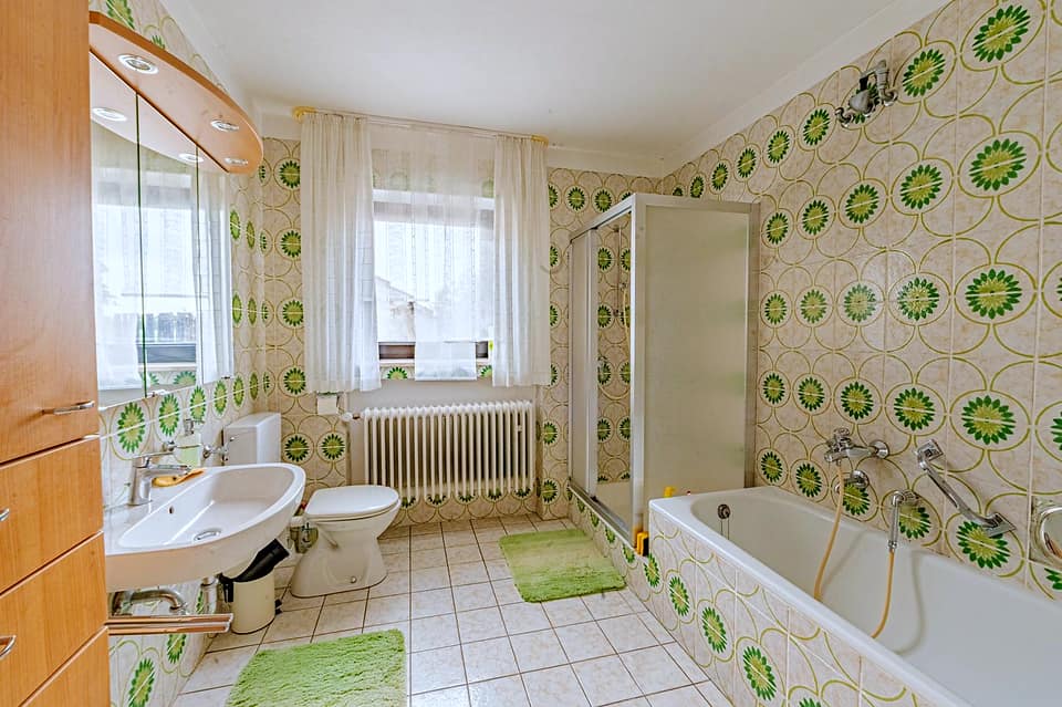 Badezimmer mit Badewanne, Bidet und grün gemusterten Fliesen