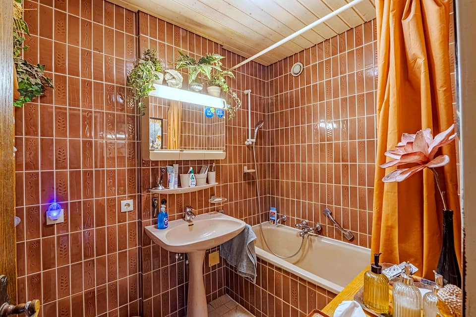 Badezimmer mit Badewanne, Waschtisch und Fliesen in Terrakotta