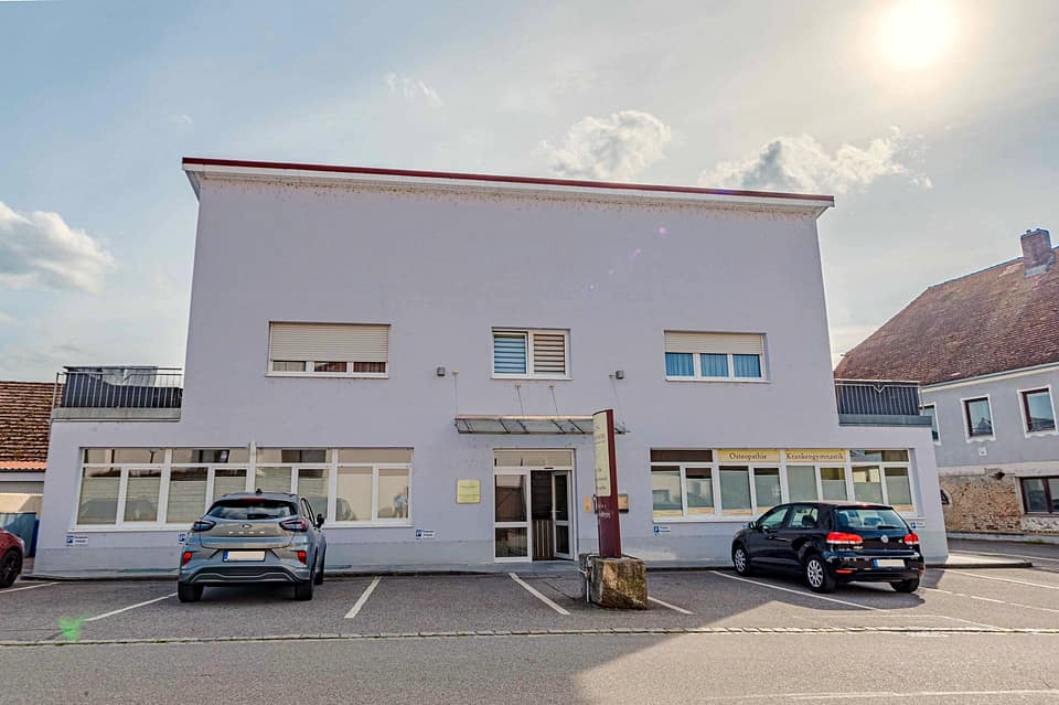 Wohn- und Geschäftshaus in Straubing-Alburg mit Ladenzeile im Erdgeschoss und Stellplätzen davor