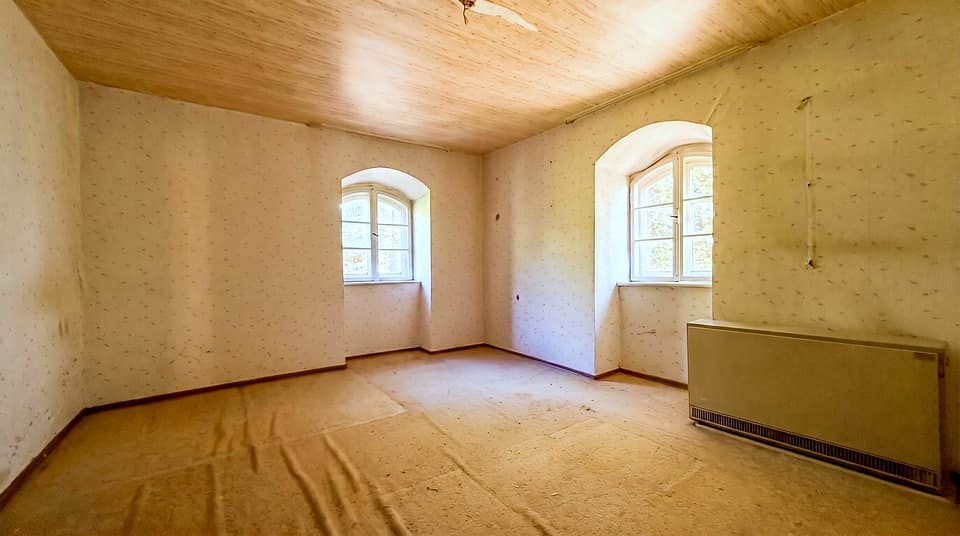 Zimmer mit zwei Rundbogenfenstern, Holzdecke und Heizkörper