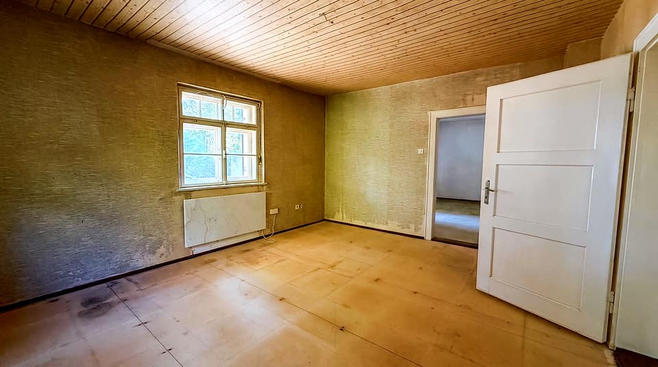 Zimmer mit Dielenboden, hohem Fenster und offener Flügeltür