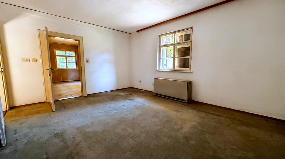 Heller Raum mit Fenster zur Gartenseite und Blick in den Nebenraum