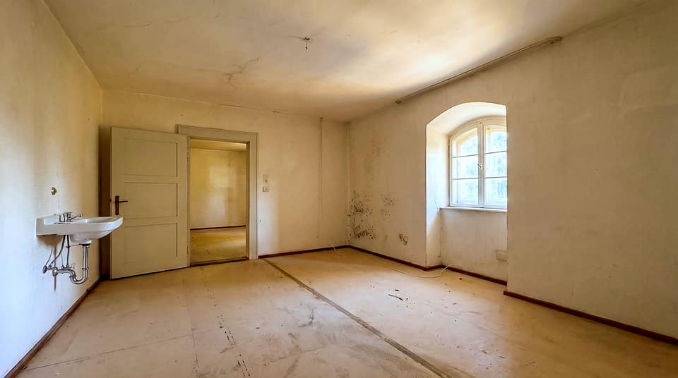 Zimmer mit Waschbecken, Rundbogenfenster und Holzdielen