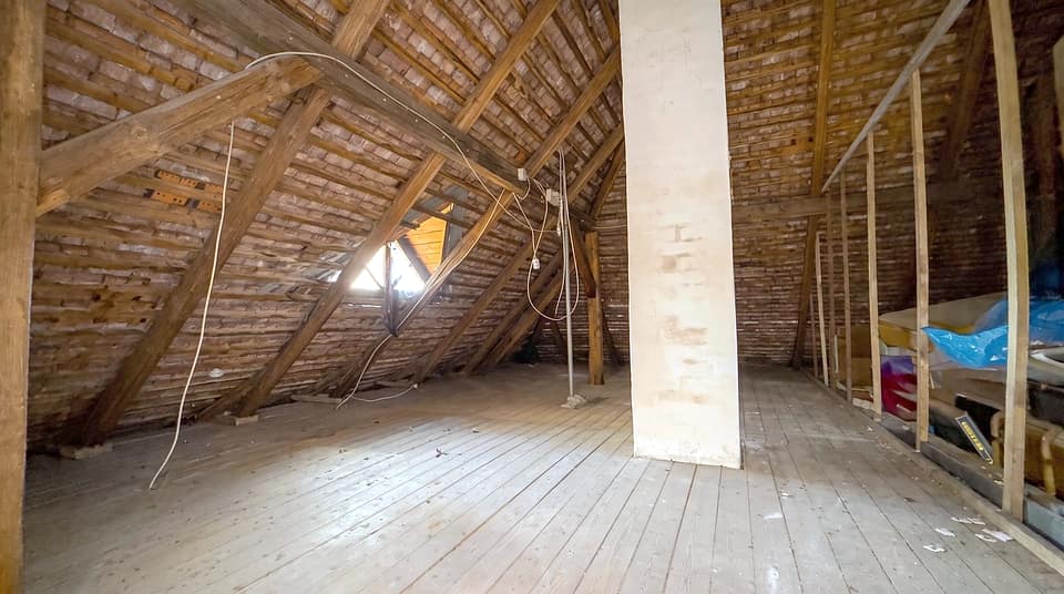 Dachboden des Hauses mit sichtbarem Dachstuhl, Ziegelmauerwerk und Dielenboden