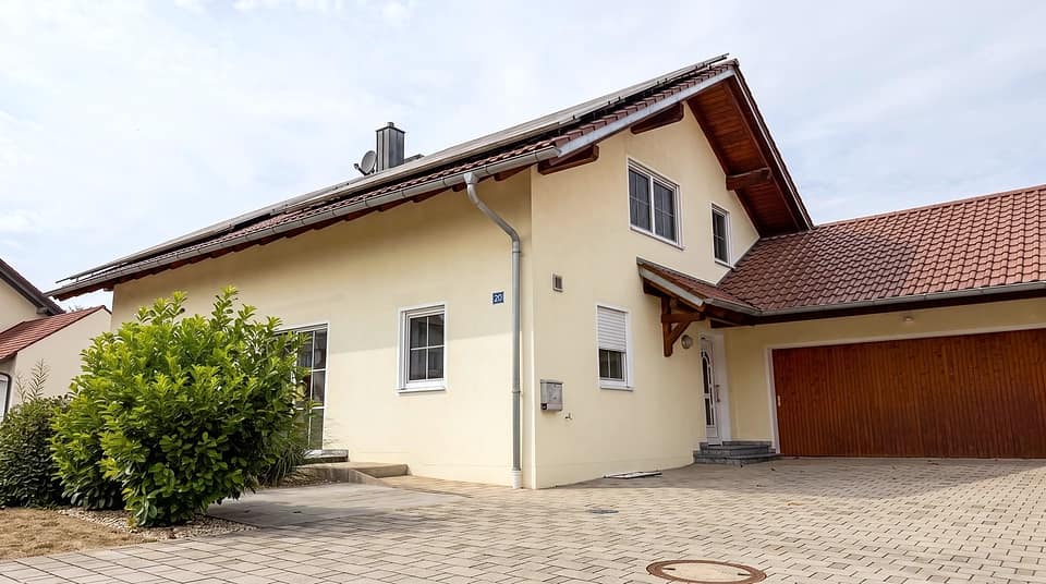 Straßenansicht des Hauses mit Garagentor, Gaube und Vorgarten