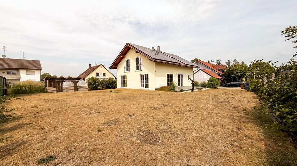 Grundstück von 899 m² mit Rasenfläche und Hecke zum Nachbargrundstück