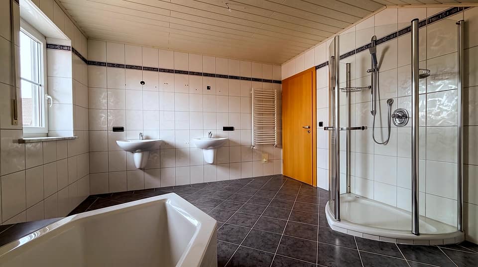 Badezimmer mit Eckdusche, Badewanne und zwei Waschbecken