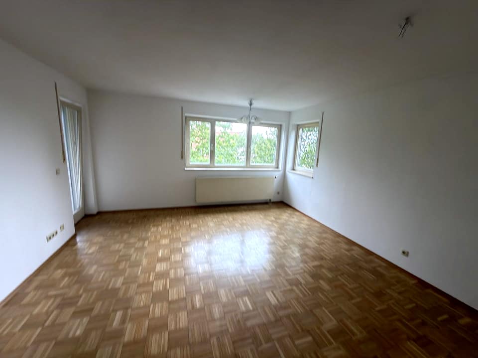 Wohnzimmer mit Parkett, Fenster und Zugang zur Loggia