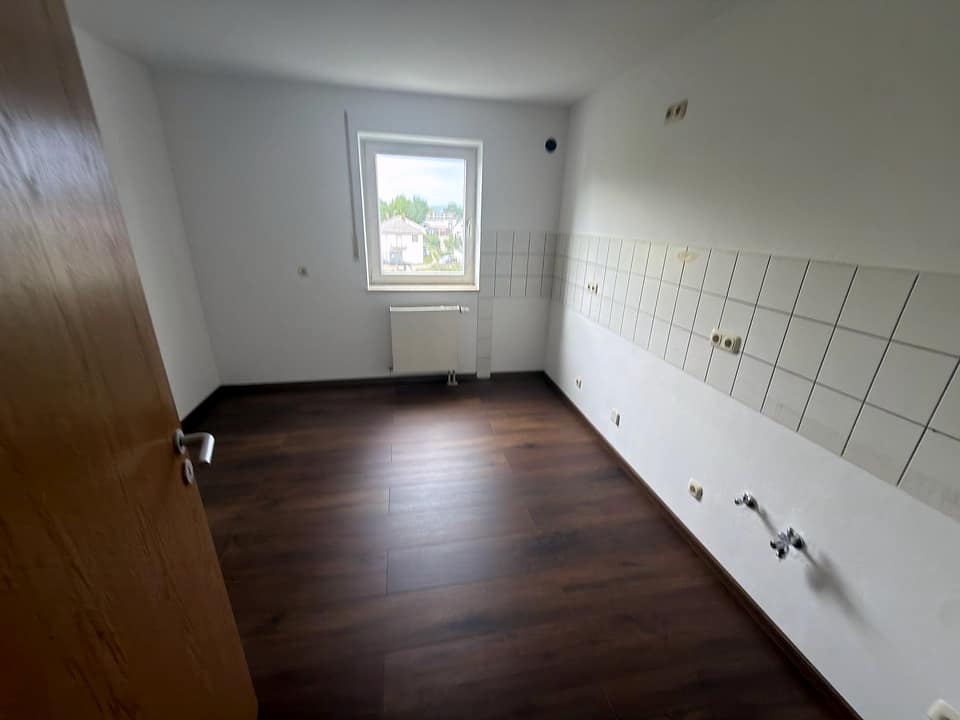 Küchenraum mit dunklem Boden, Fliesenspiegel und Anschlüssen