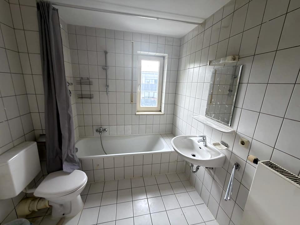 Badezimmer mit Badewanne, WC und weißen Wandfliesen
