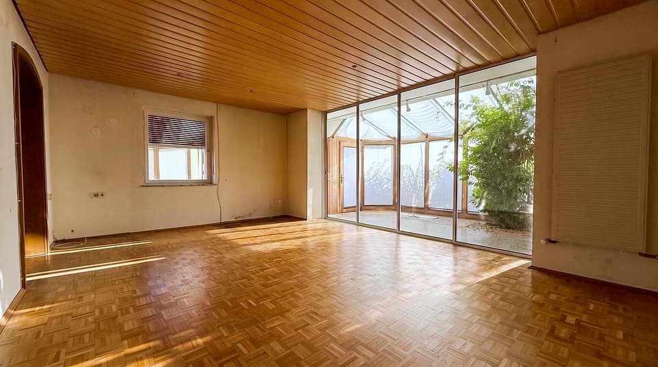 Wohnzimmer mit Parkett, Holzdecke und Durchgang zum Wintergarten