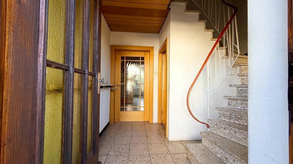 Diele mit gefliestem Boden und Treppe mit rotem Handlauf