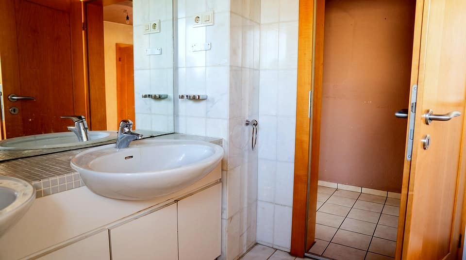 Badezimmer mit Waschtisch, breitem Spiegel und Zugang zur Dusche