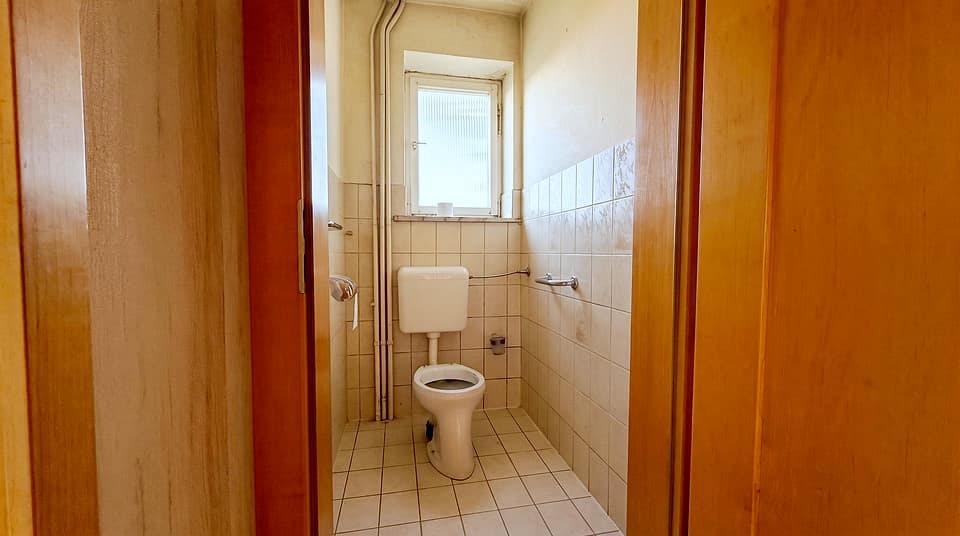 Gäste-WC mit WC, Fenster und weißen Wandfliesen