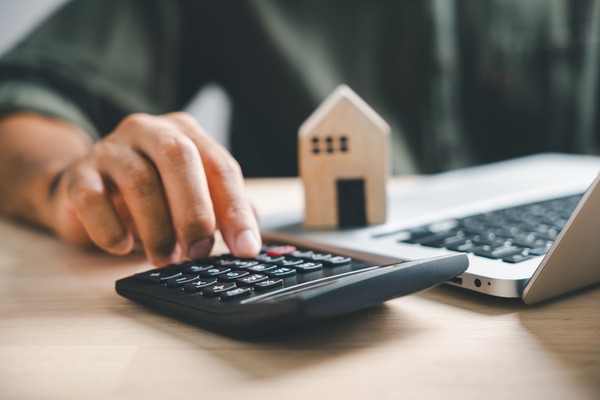 Ein Immobilienmakler führt die Immobilienbewertung mit Taschenrechner und Laptop durch