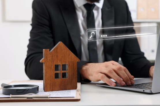 Ein Immobilienmakler sitzt für eine Immobilienbewertung am Laptop